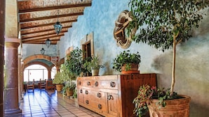 Um corredor com um armário de madeira, plantas em vasos e piso de azulejos.