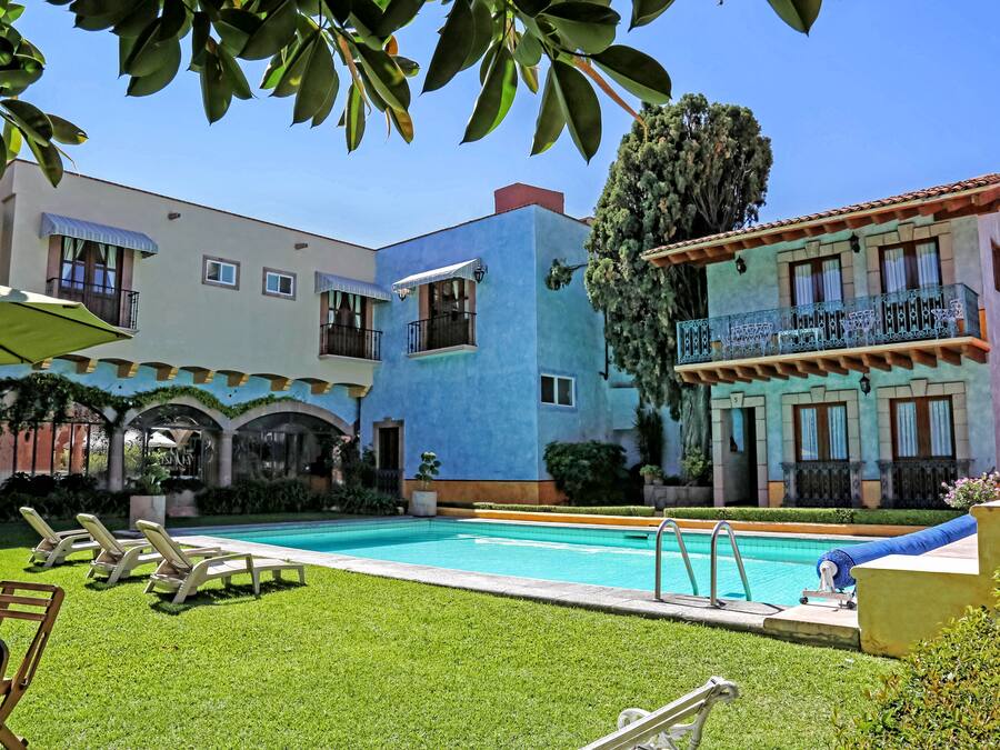 A pool area with lounge chairs, a swimming pool, and a building with balconies.