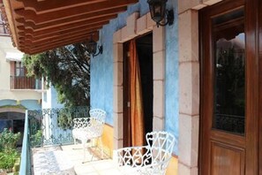 A building with a blue facade, a wooden door, and a balcony with white metal chairs. - Hotel La Plaza de Tequisquiapan (Tequisquiapan)
