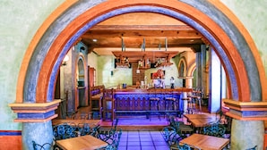 Restaurante com área de bar, mesas e cadeiras de madeira.