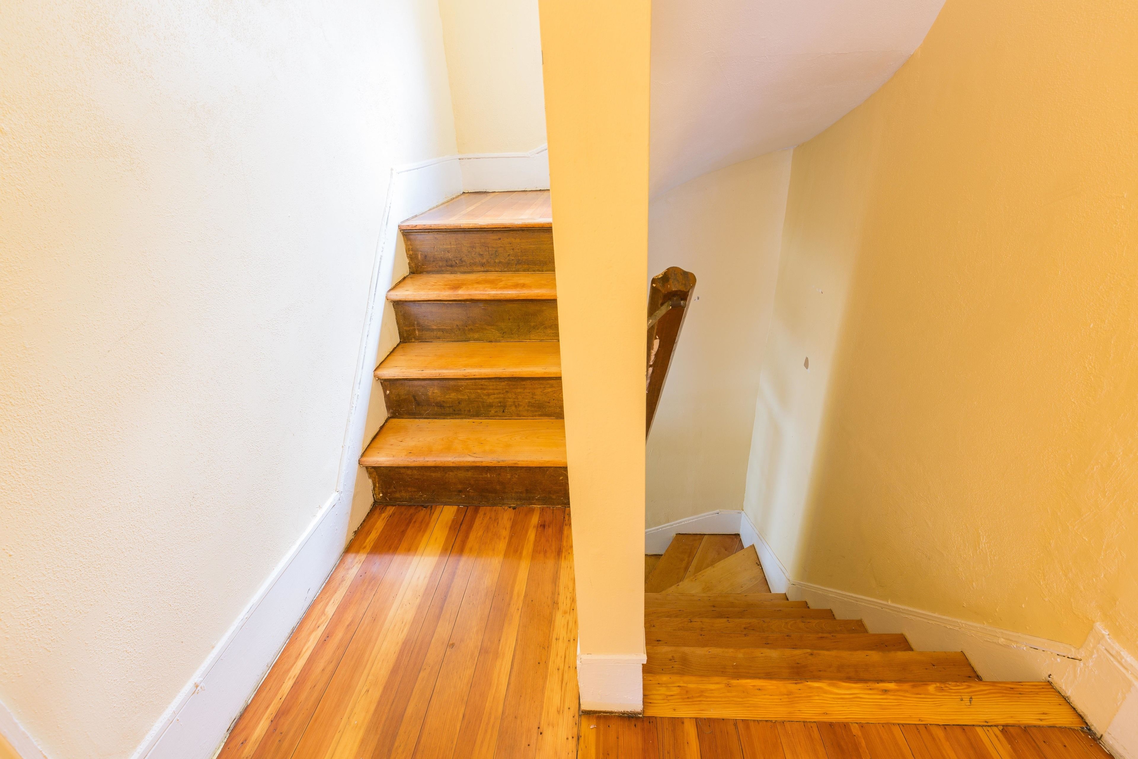 A wooden staircase with white trim and a yellow wall.