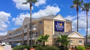 A hotel with a stone facade, multiple balconies, and a sign for In Town Suites. - InTown Suites Extended Stay Houston TX - Webster/NASA (Webster)