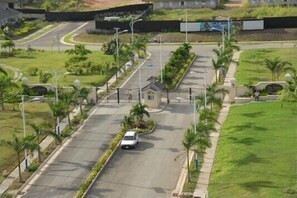 Un lotissement résidentiel fermé, avec une rue principale, un petit bâtiment et de la verdure environnante.