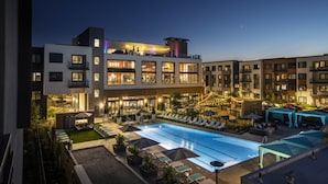 Een modern hotel met een zwembad op het dak, meerdere balkons en buiten zitplekken.