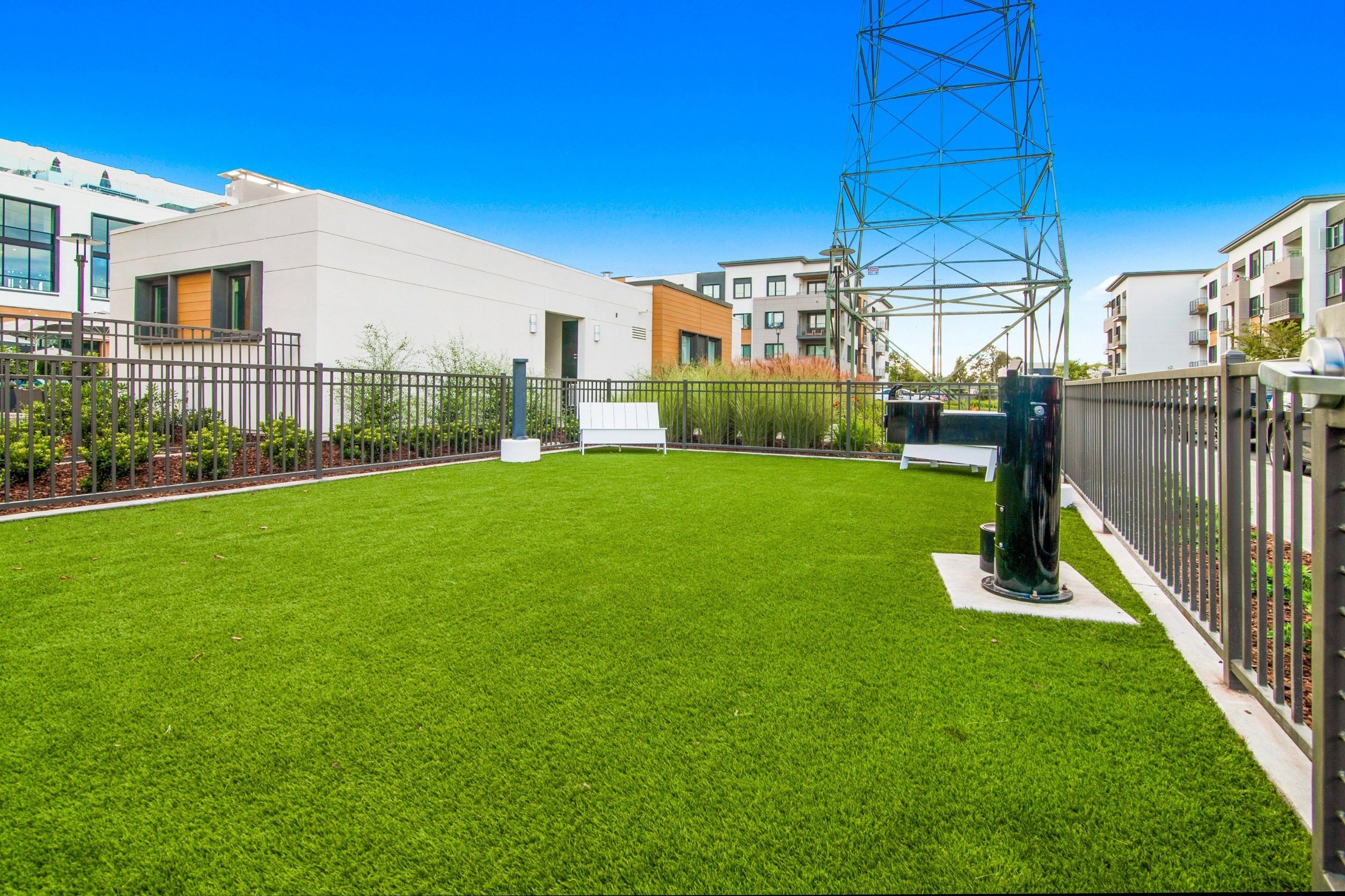 A modern residential area with a well-maintained lawn, a tall metal structure, and contemporary buildings.