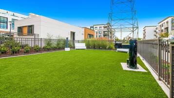 A modern residential area with a well-maintained lawn, a tall metal structure, and contemporary buildings.
