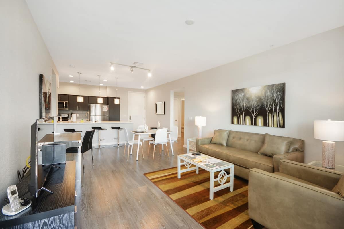 A modern living room with a sofa, coffee table, and a dining area with chairs and a table.