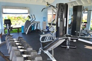 Un gimnasio con diversos equipos de ejercicio, incluyendo mancuernas, cintas de correr y máquinas de pesas.