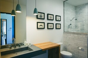 Un baño moderno con tocador de madera, un espejo grande y cuadros en la pared.