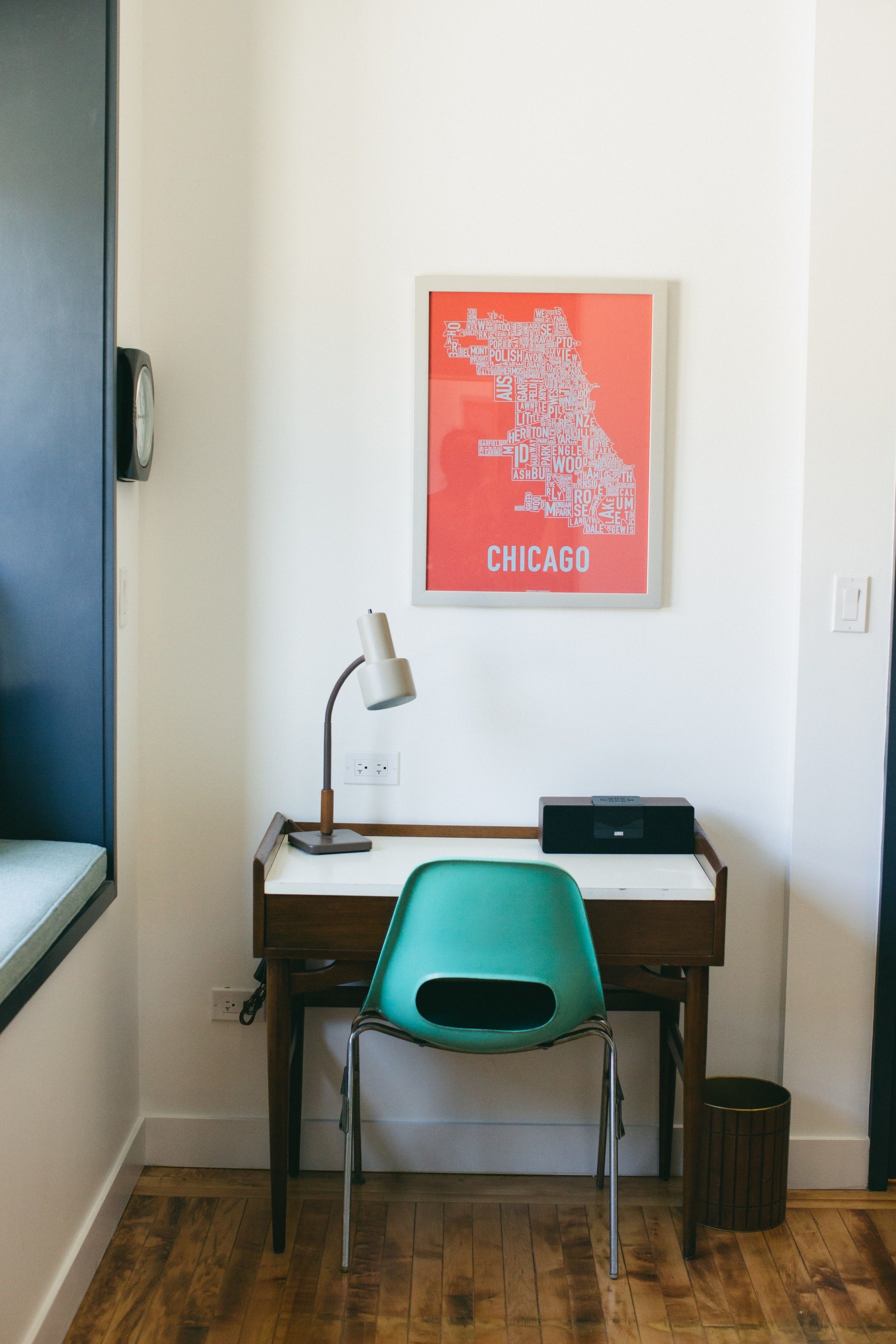 A desk with a lamp, a chair, and a framed map of Chicago on the wall.