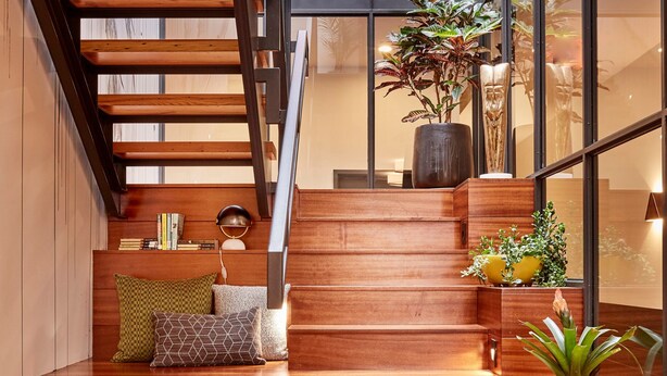A wooden staircase with built-in seating and potted plants, leading to a modern interior with large windows and a mezzanine level. - The Publishing House B&B (Chicago)