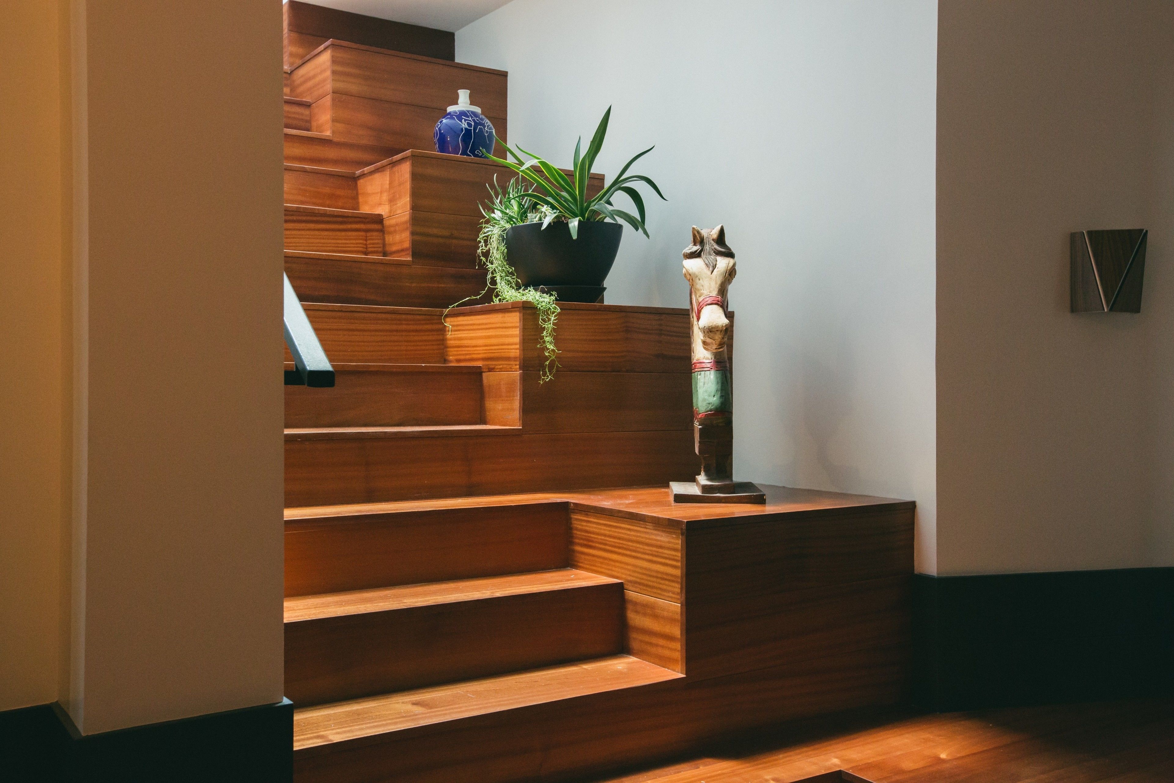 A wooden staircase with a potted plant and a decorative horse statue.