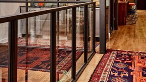 A modern hotel interior with a glass railing, a neon sign, a bar area, and a patterned rug. - The Publishing House B&B (Chicago)