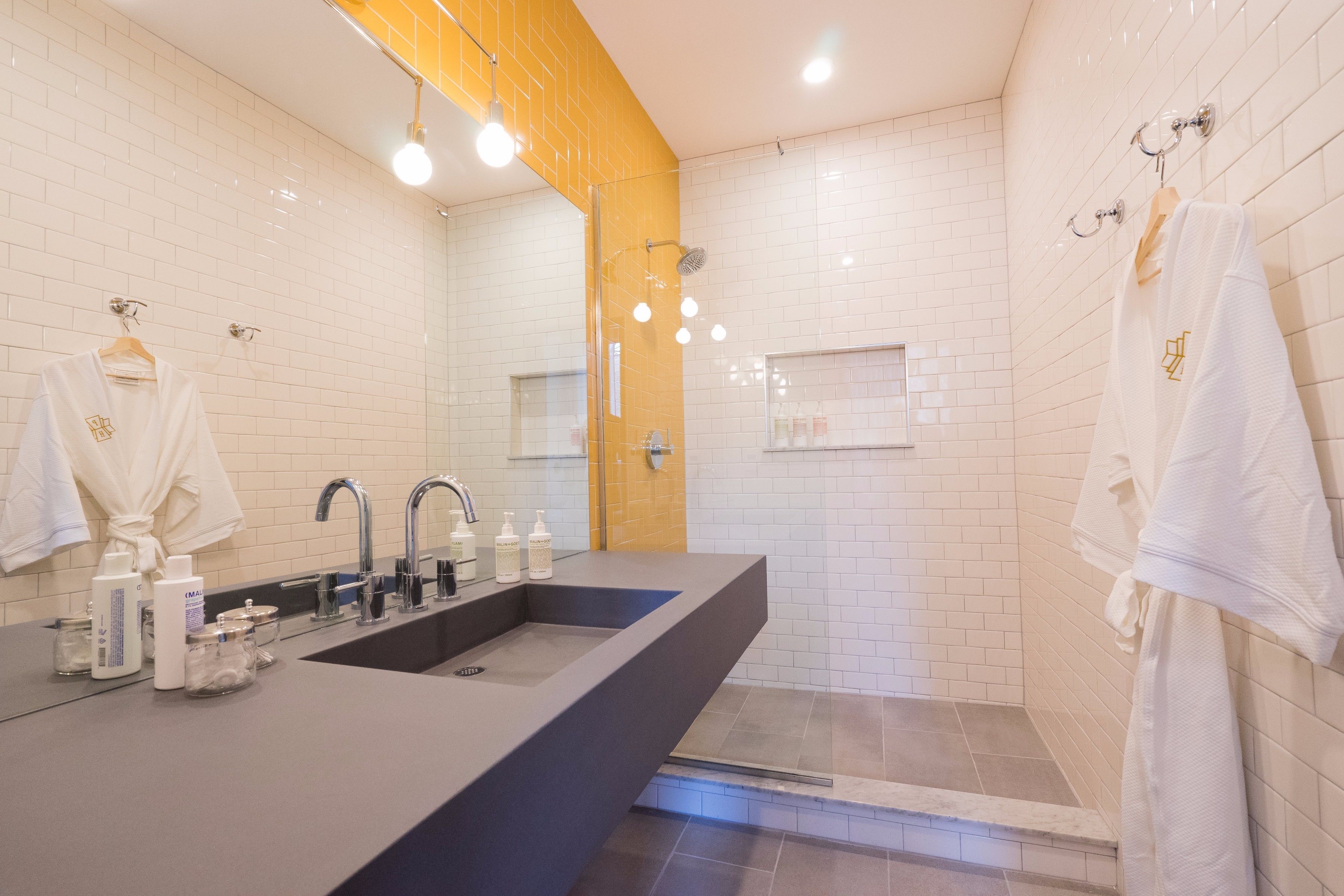 Een moderne badkamer met een groot wastafel, twee kranen en een douchegedeelte.