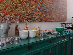 Una encimera de cocina con diferentes vasos, cuencos y un cuadro decorativo.