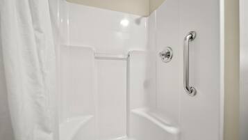 A white, empty shower stall with a grab bar and a shower curtain.