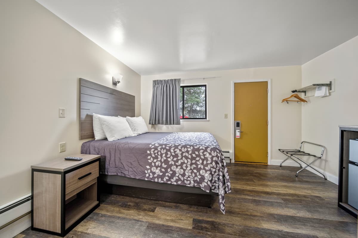 A bedroom with a bed, bedside table, and a window with curtains.
