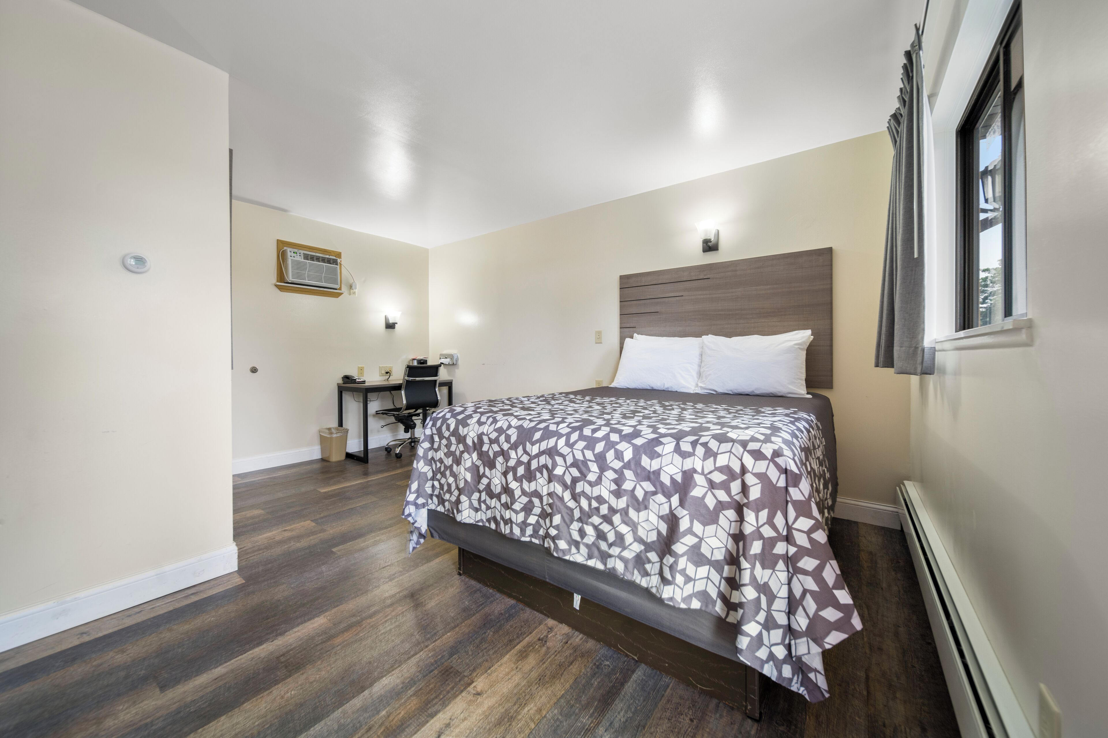 A bedroom with a bed, a desk, and a chair.