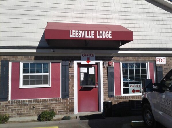 Le Leesville Lodge se distingue par son entrée rouge, une enseigne indiquant la présence de bureaux et une voiture de police garée à proximité.