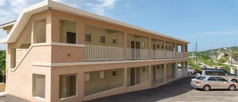 A multi-story building with a flat roof, large windows, and a parking lot.