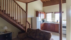 A spacious living area with a wooden staircase, a kitchen with wooden cabinets, and a dining area with a table and chairs.