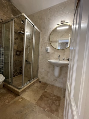 Un baño con ducha de vidrio, lavamanos y espejo.