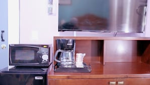 A kitchenette with a microwave, coffee maker, and a stainless steel refrigerator.