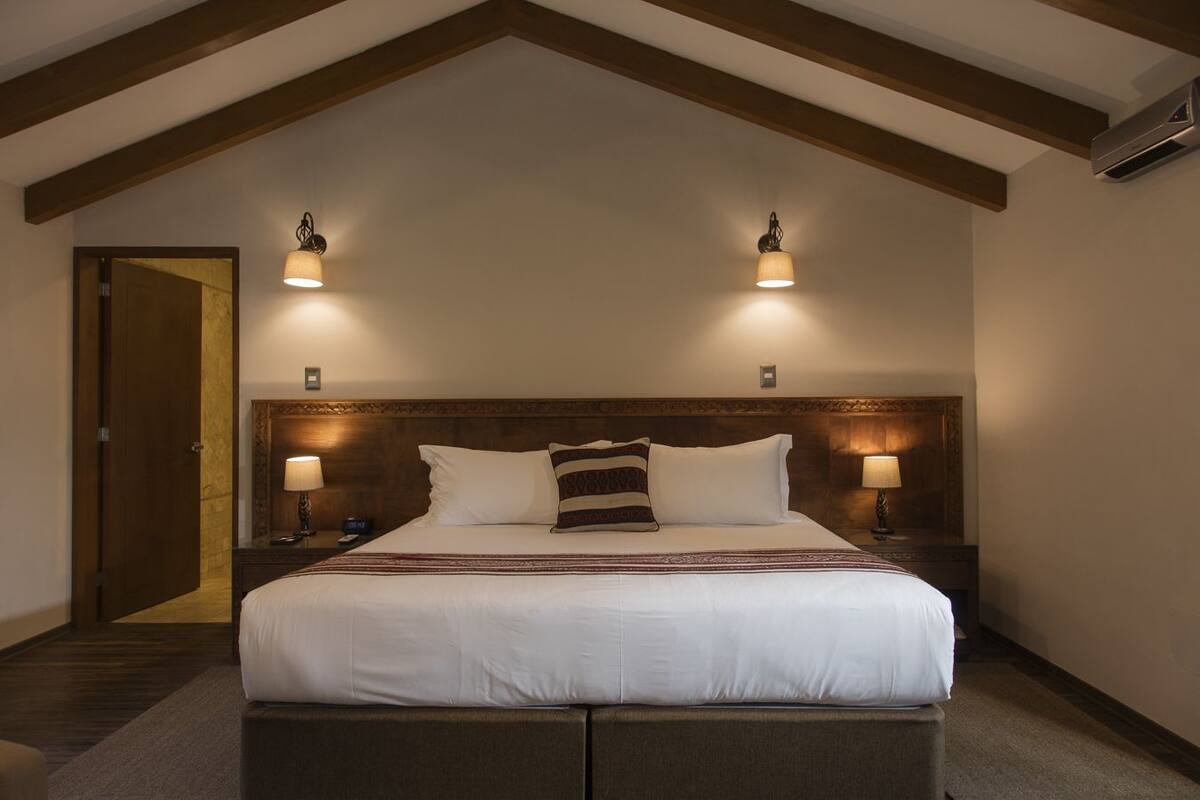 Hotelkamer met een groot bed, twee bedlampen, een houten hoofdeinde en een deur aan de linkerzijde.