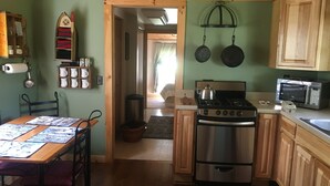 Una cocina compacta con armarios de madera, estufa, microondas y comedor con mesa y sillas.