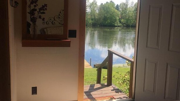 Un dormitorio con un ventanal grande que da a una terraza frente al lago.
