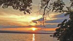 Ein Sonnenuntergang über einem ruhigen See mit einem Steg und einem Kanu am Ufer.