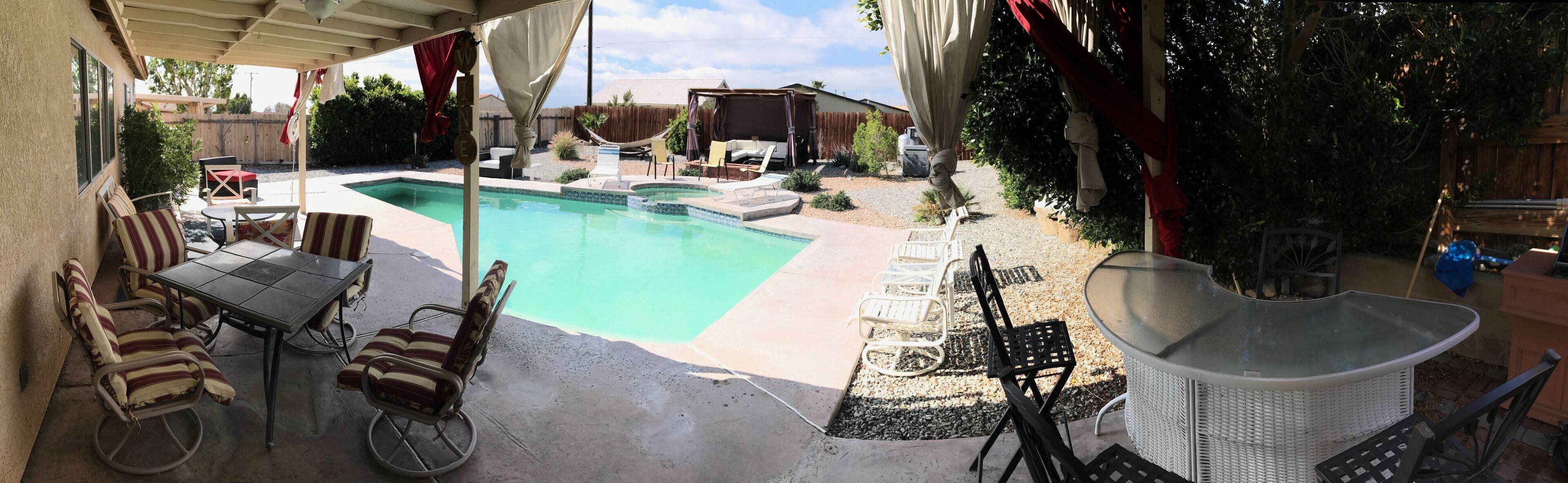 A covered patio area with a pool, outdoor furniture, and a pergola.