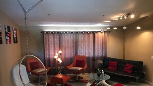 Ein modernes Wohnzimmer mit Hängekorbschaukel, zwei Sesseln, einem Couchtisch und einem Sofa.
