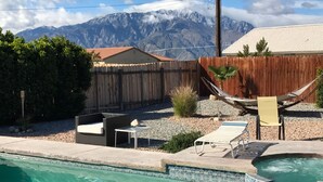 Ein Garten mit Swimmingpool, Hängematte und Bergblick.