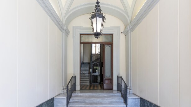 A grand staircase leading to a door, with a patterned rug at the bottom.