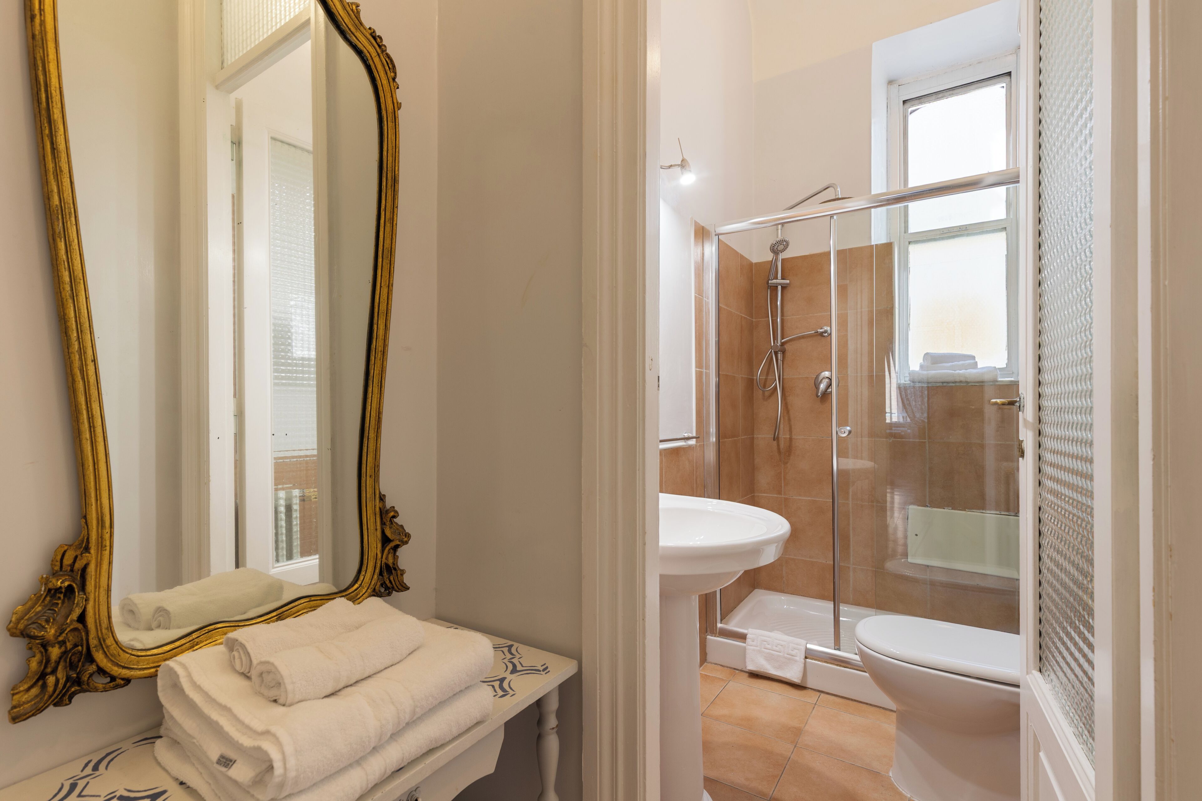 A bathroom with a large mirror, a sink, a toilet, and a shower area.
