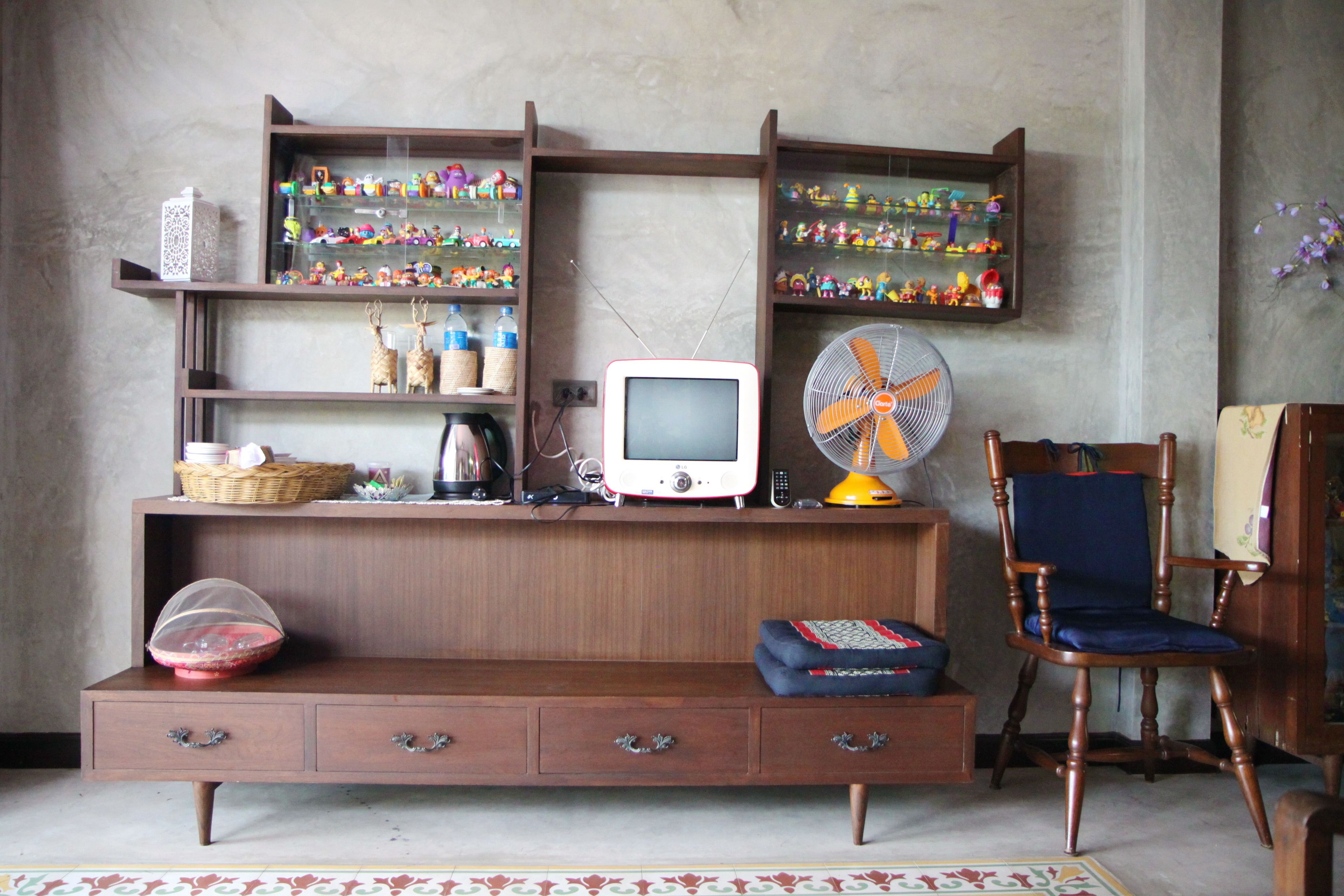 A room with a wooden entertainment center, a television, a fan, and a blue chair.