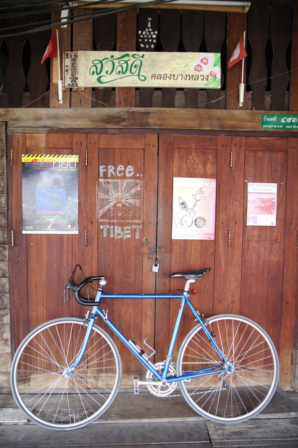 Una bicicleta azul estacionada frente a una puerta de madera con varios carteles y letreros.