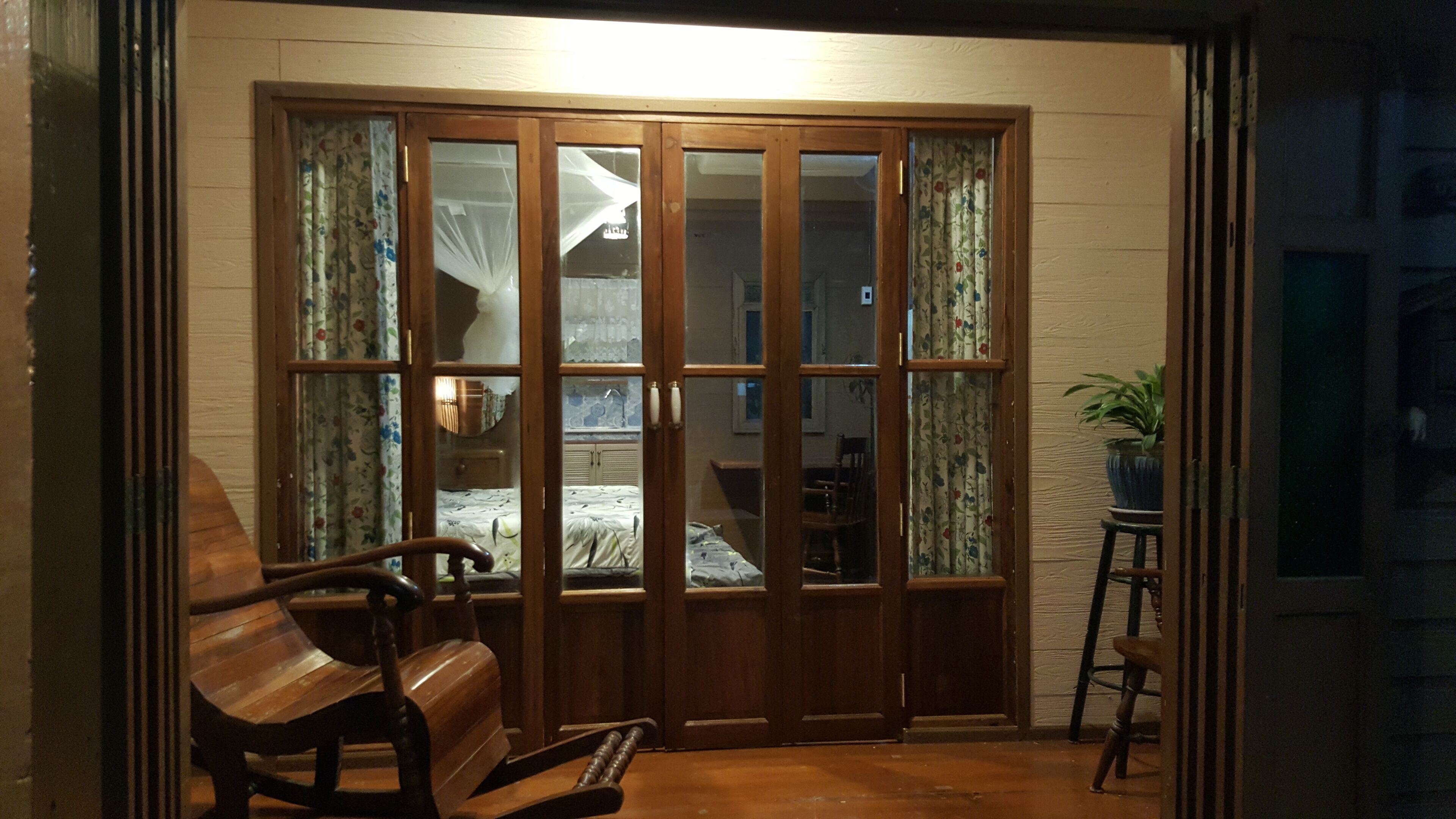 A room with a wooden sliding door leading to a bedroom, a wooden bench, and a potted plant.