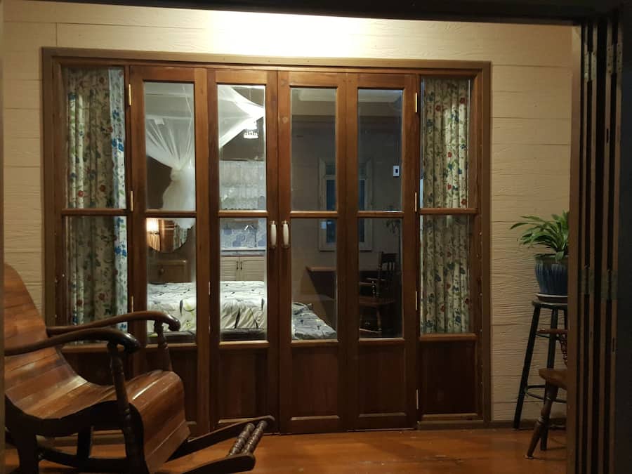 A room with a wooden sliding door leading to a bedroom, a wooden bench, and a potted plant.