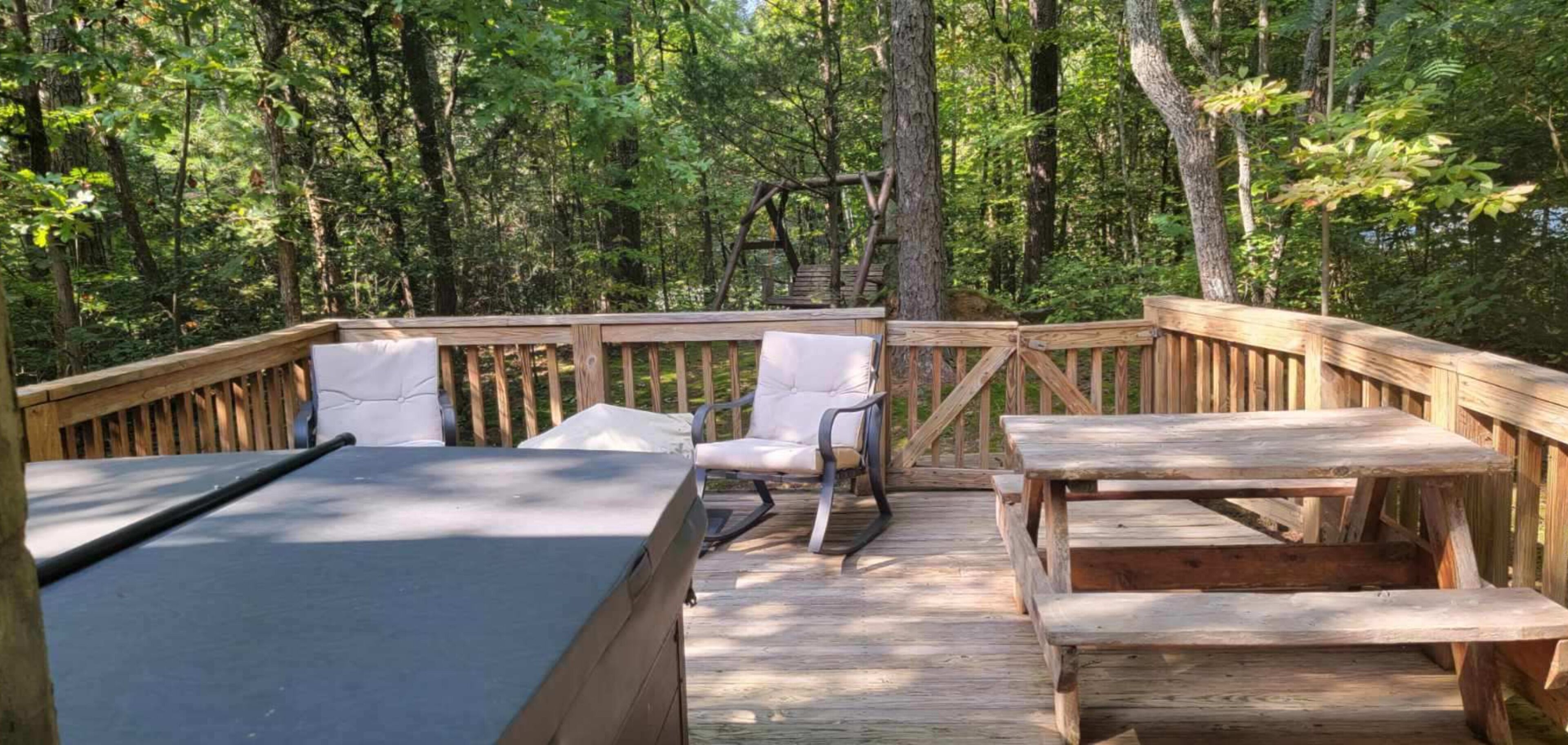A wooden deck with a table and chairs, surrounded by trees.