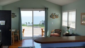 Une cuisine avec vue sur la mer, un ventilateur de plafond et un coin repas avec des chaises.
