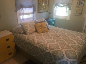 A bedroom with a bed, a nightstand, a lamp, and a dresser.