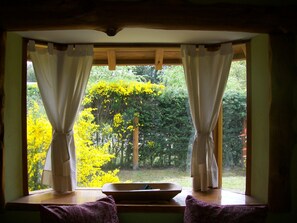 A room with a view of yellow flowering trees through a window with white curtains. - Tierras del Sur (Villa La Angostura)