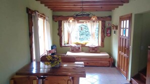 A cozy room with a wooden table, a bench, and a window with curtains. - Tierras del Sur (Villa La Angostura)