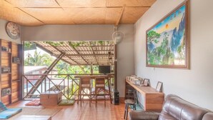 A room with a wooden ceiling, a sofa, a TV, a bookshelf, and a painting. - Sor Vorapin Muay Thai Home (Bangkok)