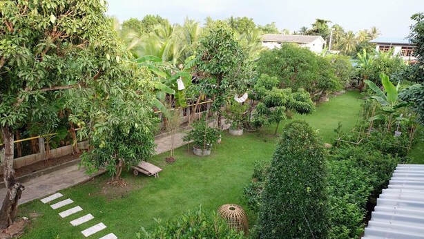 A lush garden with a variety of trees and a small wooden bench. - Sor Vorapin Muay Thai Home (Bangkok)