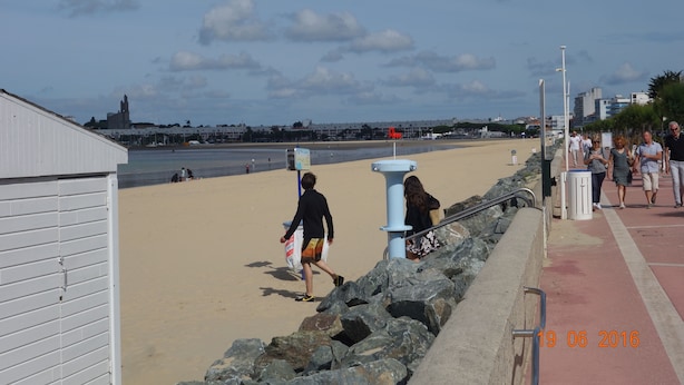 A beachside walkway with a stone wall, a blue pillar, and a white building. - T3 - Quartier Le Parc 200 m from the beach, parking, elevator, terrace, shops (Royan)