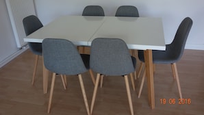 A rectangular dining table with four grey upholstered chairs with wooden legs. - T3 - Quartier Le Parc 200 m from the beach, parking, elevator, terrace, shops (Royan)
