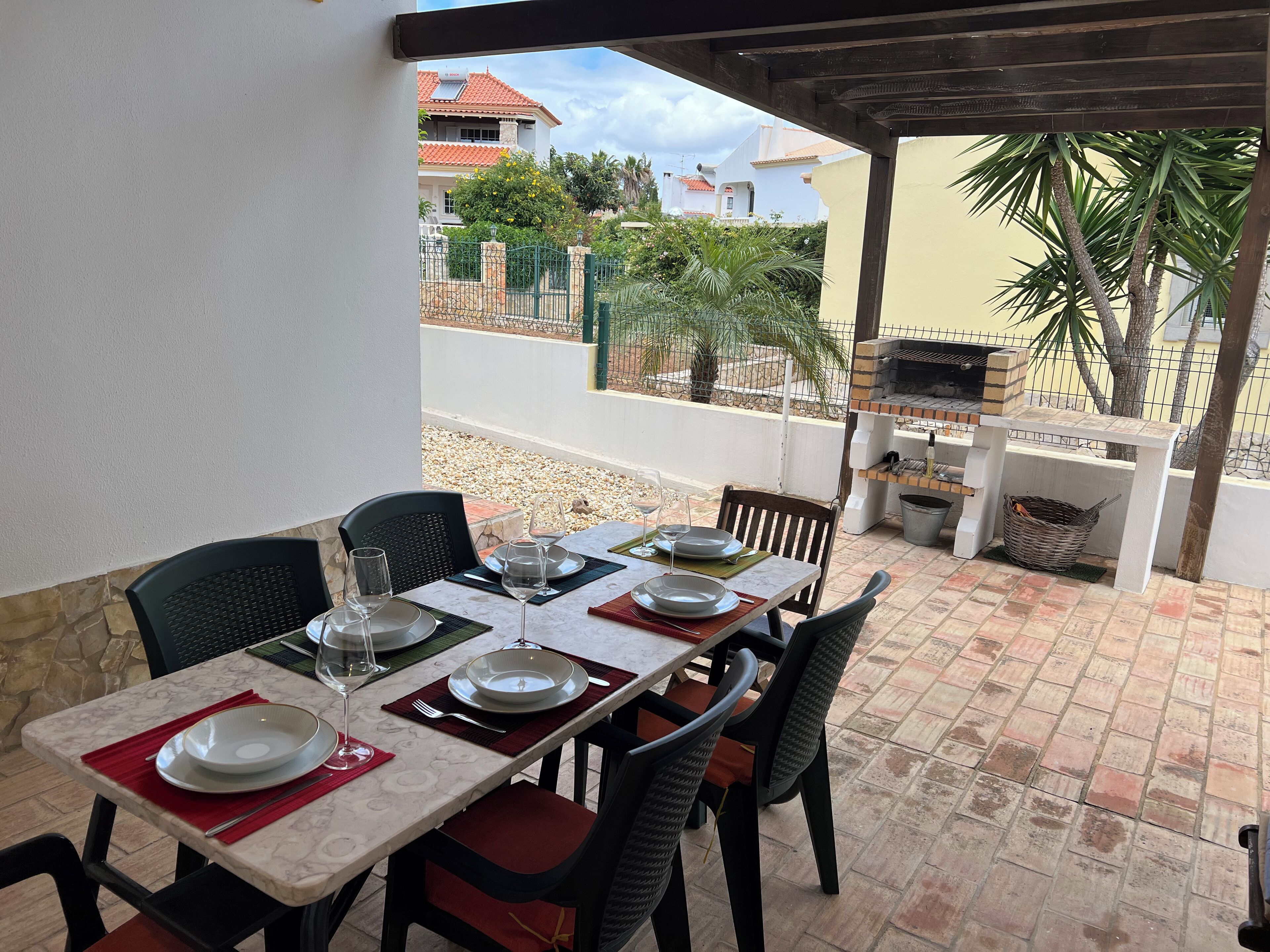 An outdoor dining area with a table set for four, surrounded by chairs.